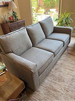Front three-quarter view of gray tweed three-seat couch in living room setting