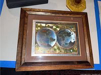 Framed vintage-style world map in brown wooden frame with hemispheres and celestial illustrations