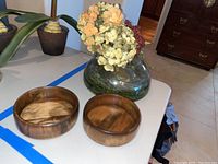 Wooden bowls and glass vase with artificial flowers arranged on table