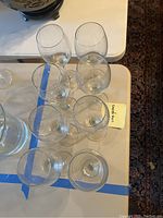 8 clear glass wine glasses on a table from a slightly elevated angle showing their size and shape.