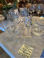 Photo showing 4 plastic wine glasses, 3 painted champagne glasses with floral design, 2 crystal champagne glasses, and 2 crystal ice buckets