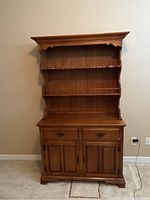 Full view of the two-piece wooden hutch showing upper shelving and lower cabinet doors with drawers.