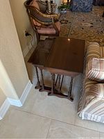 Three wooden nesting tables shown placed together, viewed from front corner angle highlighting their size difference and polished tops.