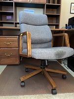 Front view of grey upholstered office chair with wooden armrests and base, showing overall condition and design.