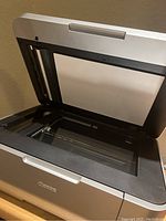 Canon printer and scanner unit with lid open showing glass scanning surface and inside area.