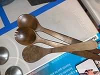 Three wooden cooking spoons stacked together showing different spoon types and a smooth wood finish.