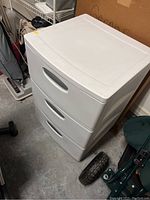 White plastic Sterilite three drawer storage container shown from front angle with visible top and drawer handles.