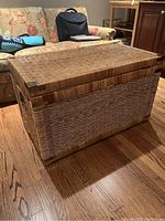 Angled view of wicker trunk showing lid and overall rectangular shape.