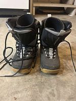 Front view of pair of black and gray Airwalk women's snowboard boots, size 4, with tan soles and laces untied.