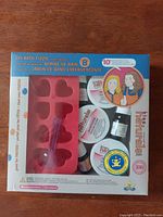 Front view of the Kiss Naturals DIY Bath Fizzie Kit showing product contents through clear packaging including silicone mold, ingredient containers, spoon, and fragrance oil.