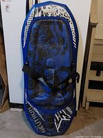 Full view of the blue knee board with strap and abstract black graphic design.