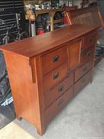 Side view of the mahogany dresser showing the side panel and drawer fronts with metal handles, wood grain visible.