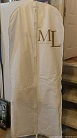 Full view of a white garment bag with Melanie Lyne logo, protecting the dress inside.