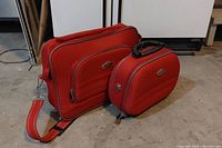 Photo showing both Millennium travel bags side by side placed on the floor, highlighting size difference and orange color.