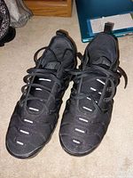 Pair of black Nike Air Vapormax Plus men's shoes with visible reflective detailing and air sole. Shown from top view.