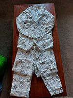 Full view of the pajama set laid flat on table showing the floral and bird print with long-sleeve buttoned top and matching pants.