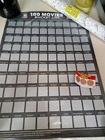 Full view of the scratch poster rolled and unrolled horizontally showing empty scratch boxes and coin tool.