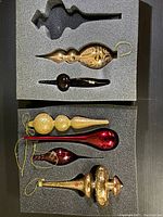 Top view showing six vintage glass Christmas ornaments neatly placed in foam padding in two layers.