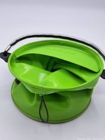 Top view of bright green Colapz collapsible camping shower showing the flexible fold and black hanging cord.