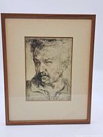 Framed artwork featuring a male portrait etching with visible matting and wood frame.