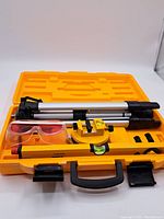 Kit contents arranged in open yellow carrying case including tripod, laser level, safety glasses.
