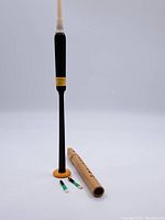 Full view of black recorder with yellow accent and bamboo flute with accessories.