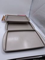 Three stacked KitchenAid baking sheets showing variety of sizes and condition.
