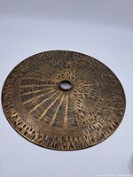 Top view of the metal gong showing the full round shape, central hole, and detailed engraved patterns on the surface with dark antiqued bronze finish.