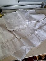Vintage white tablecloth and linen piece spread on a flat surface showing lace insets and hemstitching.