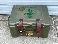 Overall view of the vintage army barrack box showing top with stencil text and military patches.