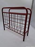 Photo of the vintage red metal Ikea magazine rack showing the grid wire structure and tubular frame.