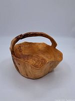 Full view of the wooden bowl showing its organic shape and integrated handle.