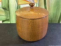 Front view of the vintage wooden jar with lid, showing rounded shape, wood grain and knob handle on lid.