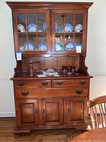Front view of the complete Sterling House cherry wood dining room hutch showing upper glass doors with wood grid framing, cherry wood finish, lower cabinet with drawers and doors.