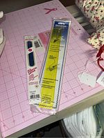 Close up of pink 36x24 rotary cutting mat with two Omnigrid rulers packaged and loose