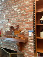 Wide view of four wooden animal silhouettes placed on a mantel with brick background and vintage sleigh bells mounted vertically beside them.