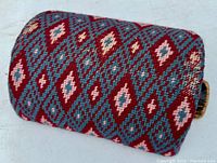 Close-up of embroidered wool fabric in red, blue, white diamond pattern on stool surface