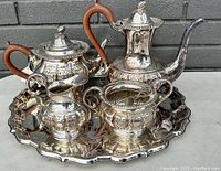 Front and top view of entire antique silverplated tea set showing tea pot, coffee pot, creamer, sugar bowl on ornate tray