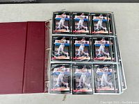 Front view of open 3-ring binder with first sleeve page filled with 9 baseball cards featuring Chris Carpenter in various poses.
