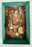Top-down view of a filled box with assorted old pennies and some silver coins visible beneath