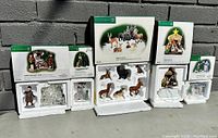 Wide shot of all boxed Department 56 Dickens Village Series ceramic figurines and accessories arranged outdoors showing packaging and contents.