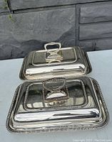 Two silver plated entree servers rectangular with lids and removable handles, polished surface, ornate borders.