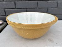 Side view of the TG Green Gripstand mixing bowl showing yellow textured exterior and white glazed interior.