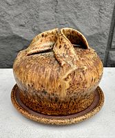 Side view of the handmade pottery butter dish with wild speckled brown glaze, showing the lid with two raised handles.