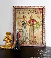 Front view of the decoupaged frame showing the full artwork of two women with 'Carte Postale' text and surrounding staging items.