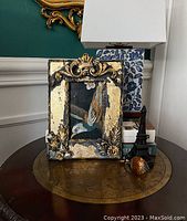 Full view of the decorative picture frame displaying black chalk paint and gold leaf overraised moldings with baroque styling.
