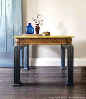 Full view of the side table showing the decoupaged top, gold leaf accents, and carved legs.