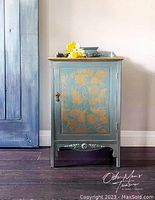 Full view of the vintage music cabinet showing the front door with floral stencil and carved details.