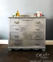Front view of the four-drawer dresser showing painted surface, drawer hardware, and decorative motifs.