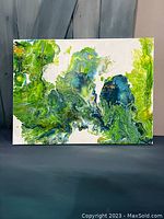 Front view of the acrylic poured canvas art, showing swirling patterns in green and blue with a white background.